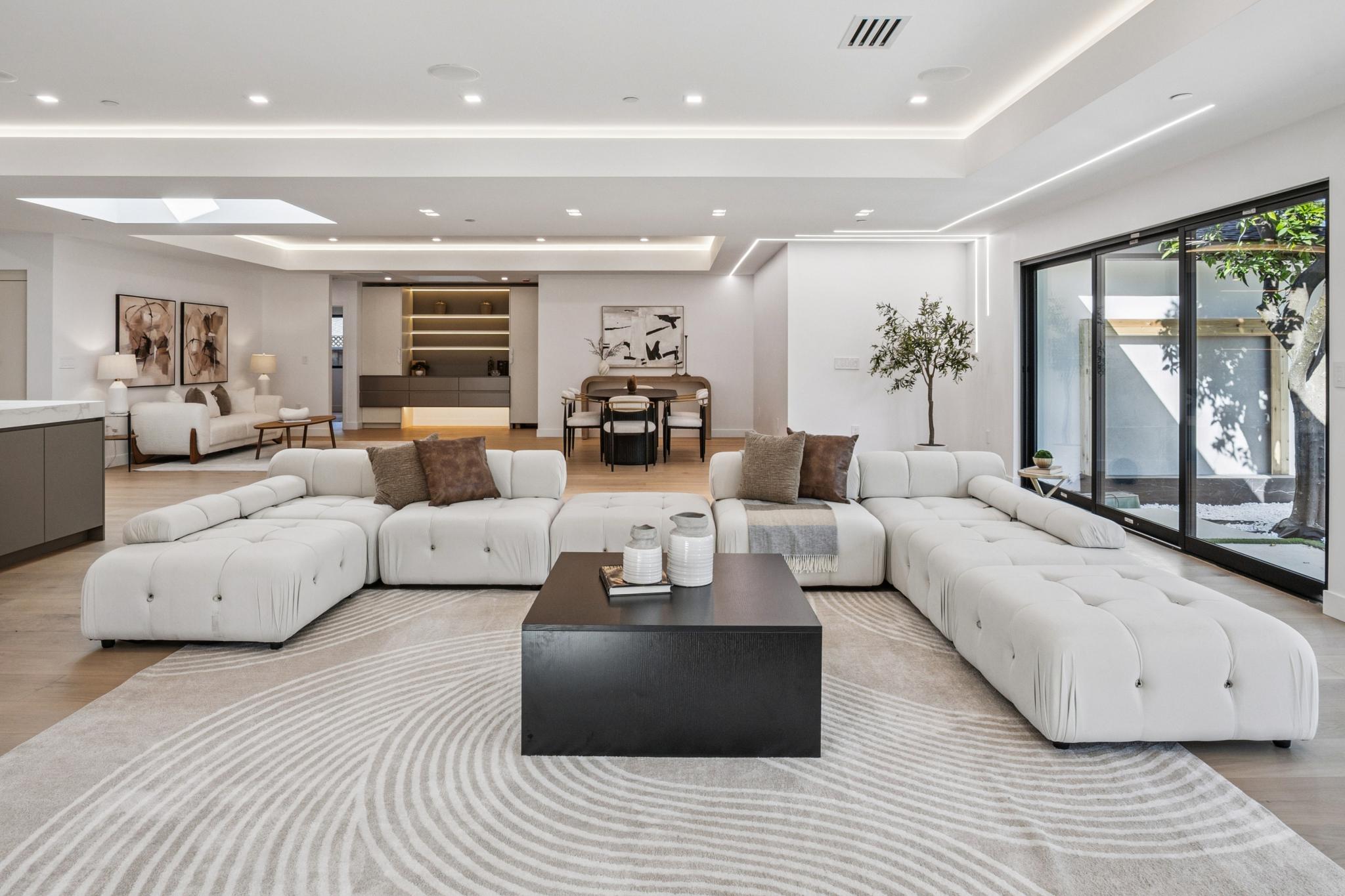 Modern custom home living area in Willow Glen, San Jose, featuring large black-framed sliding glass doors for an effortless indoor-outdoor flow to the private backyard.